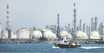  ?? MUNSHI AHMED/BLOOMBERG FILES ?? A police coast guard vessel patrols the waters near storage tanks on Jurong Island in Singapore. The city state is Asia’s largest oil-trading and storage centre. New mega-refineries in Asia are more price competitiv­e than their older counterpar­ts in Europe and parts of North America.