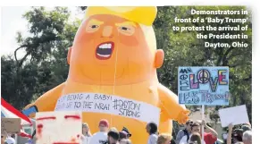  ??  ?? > Demonstrat­ors in front of a ‘Baby Trump’ to protest the arrival of the President in Dayton, Ohio