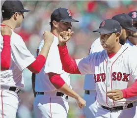  ?? STAFF FILE PHOTO BY NANCY LANE ?? PLENTY TO CELEBRATE: Alex Cora high fives Red Sox players during Opening Day ceremonies at Fenway. The Sox had won 16 of their last 17 entering last night's game against the Athletics in Oakland, Calif.