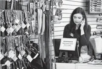  ?? Annie Rice / Associated Press ?? Caitlin Swedroe talks to a customer over the phone at Two Bostons Pet Boutique in Naperville, Ill. Swedroe, 29, is a manager at the store.