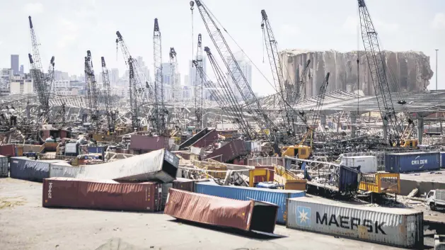  ??  ?? Destroyed freight containers sit under cranes against the backdrop of grain silos damaged in an explosion last week at the Port of Beirut in Lebanon’s capital, Aug. 9, 2020.