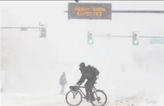  ?? Michael Ciaglo / Getty Images ?? People cross Colfax Avenue in Denver in the storm. Thousands of flights at the Denver airport were canceled over the weekend and highways around the state were closed during the storm.