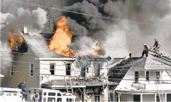  ?? JACQUELINE DORMER/POTTSVILLE REPUBLICAN-HERALD ?? Flames tear through the roof of a house in Tower City on Tuesday. A woman in the adjoining home was able to escape with two dogs.