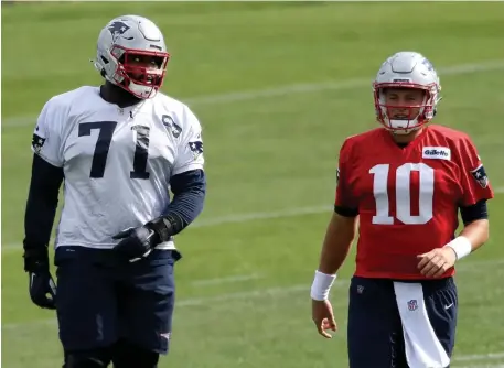  ?? NAncy lAnE / HErAld stAFF ?? WELCOME BACK: Patriots offensive lineman Mike Onwenu, fresh off the COVID-19 reserve list, runs through warmups with quarterbac­k Mac Jones during Thursday’s practice.