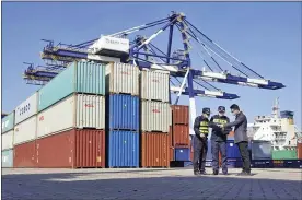 ?? CHINATOPIX VIA AP ?? Custom officials check documents with a man at a container port in Yantai in eastern China’s Shandong province on Tuesday.