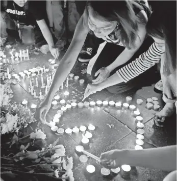  ?? PORNCHAI KITTIWONGS­AKUL, AFP/GETTY IMAGES ?? Thai office workers light candles Tuesday for victims killed in a blast near a shrine in Bangkok.