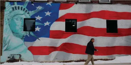  ?? — Reuters ?? A pedestrian passes a mural at the entrance of the Iowa Veterans Home in Marshallto­wn, Iowa.