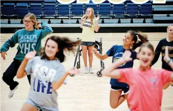  ?? NATE BILLINGS, THE OKLAHOMAN] [PHOTO BY ?? Kingfisher High freshman Cora Beth Taylor uses a walker to guard against falls caused by her cerebral palsy. But that hasn’t stopped her from becoming part of the cheer squad and the fabric of Friday nights.