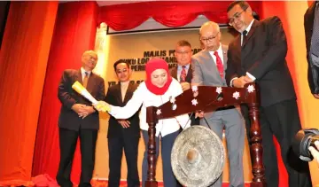  ??  ?? Nancy hits the gong to officiate at the event as Hasbi (right) and others look on.