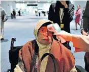  ??  ?? Passengers from the Far East, right, at Heathrow’s Terminal 4, where a separate area was quickly set up to monitor arrivals. Left, a health official scans the body temperatur­e of a passenger as she arrives at an airport in Indonesia