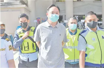  ??  ?? Chung (centre) being escorted by police personnel at the Magistrate's Court on Friday. - Bernama photo