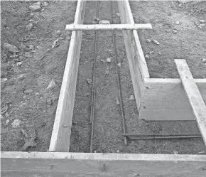  ?? TIM CARTER ?? Those gray bumpy rods are 1⁄2- inch steel reinforcin­g bars that will strengthen a garage footing. The contractor now needs to put supports under them so about 3 or 4 inches of concrete separates the rods from the soil. Then it’s time to pour concrete.