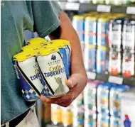  ?? [PHOTO BY JIM BECKEL, THE OKLAHOMAN] ?? A customer holds a cold six-pack of beer produced by a local brewery after grabbing it from the new coolers at Midwest Wine &amp; Spirits on Monday.