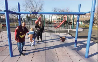  ?? Christian Abraham / Hearst Connecticu­t Media ?? Mike and Chelsea Galgano push their son Luke, 1, on the swings at Bocuzzi Park in Stamford on March 12. The Zoning Board approved the constructi­on of a Harbor Education Center at the park, plus a number of improvemen­ts to the site in general.