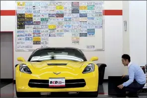  ?? Tribune News Service/TAKAAKI IWABU ?? Atsuto Nishimura of Mitsuoka Motor, a dealership featuring American cars in Yokohama City, Japan, sets up a Corvette display in October. In 2013, just 0.03 percent of cars sold in Japan were American.
