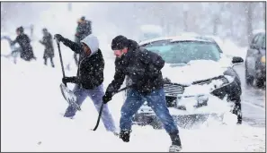  ?? AP/Star Tribune/JERRY HOLT ?? Neighbors John Bauer (right) and Fahmi Osman help residents dig their vehicles out of the snow Sunday in Minneapoli­s.