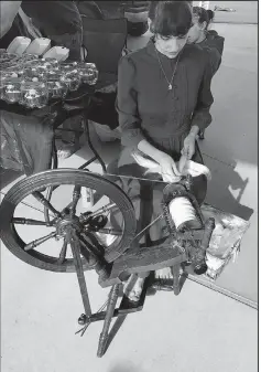  ?? Photo by Richard Mason ?? Delaney Durheim shows how an old-fashioned spinning wheel works at Murphy Arts District’s newly opened Playscape.