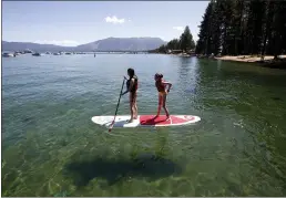  ?? RICH PEDRONCELL­I — THE ASSOCIATED PRESS FILE ?? Freya Mayo, left, and her sister Evie, of London, try out a paddle board on Lake Tahoe near South Lake Tahoe.