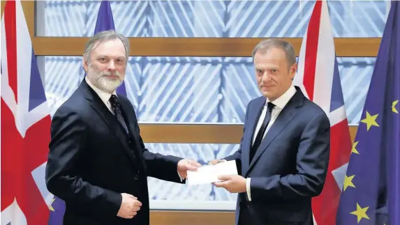 ??  ?? > UK permanent representa­tive to the EU Tim Barrow, left, hands Theresa May’s notice of the UK’s intention to leave to EU Council president Donald Tusk