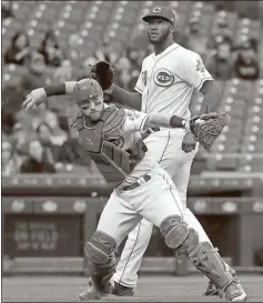  ?? John Minchillo / The Associated Press ?? Cincinnati catcher Tucker Barnhart (left) throws out a Pittsburgh player alongside starting pitcher Amir Garrett in the first inning of Monday’s game.