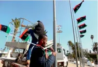  ?? AFP ?? Libyan workers hang flags to decorate Tripoli’s Martyrs’ Square in preparatio­n for celebratio­ns marking the sixth anniversar­y of the start of the armed revolt that ousted Muammer Gaddafi. —