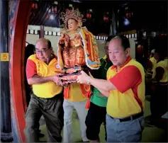  ??  ?? Two devotees carry the statue of a deity to a procession float.