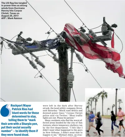  ??  ?? The US flag lies tangled in power lines as strong winds from Hurricane Harvey hits Corpus Christi, Texas on August 25, 2017. AFP / Mark Ralston A group of people race across the street as winds from Hurricane Harvey escalated in Corpus Christi, Texas,...