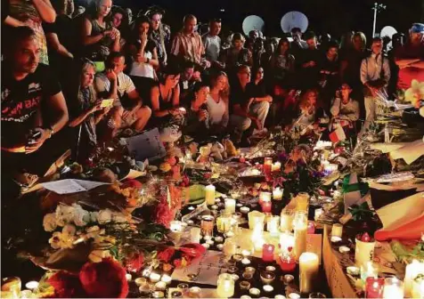  ??  ?? People gather around a makeshift memorial to pay tribute to the victims of the attack in Nice on Friday, a day after a man drove ■ a truck through the crowd celebratin­g Bastille Day, killing at least 84 people.