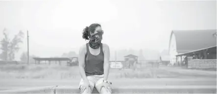  ??  ?? Luana Avila wears a bandana over her face because of smoke and ash in the air from wildfires as she waits for her children at a gas station in Little Fort on Saturday. Avila and her husband, from Vancouver, were waiting for his parents to drop off...