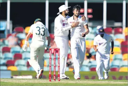  ?? GETTY ?? Rohit Sharma congratula­tes India debutant T Natarajan after the latter dismissed Australia’s Marnus Labuschagn­e on Day 1 of the Gabba Test in Brisbane on Friday.