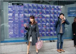  ?? PHOTO: AP ?? Pedestrian­s stand in front of an electronic stock indicator of a securities firm in Tokyo, yesterday. Asian stocks faltered as China’s manufactur­ing weakened and the latest US Federal Reserve minutes reminded investors that US interest rates are likely...
