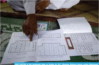  ??  ?? COX’S BAZZAR: In this photograph taken on October 20, 2017, Myanmar Rohingya Islamic scholar Muhammed Hanif shows an example of a textbook as he speaks during an interview with AFP at a madrassa. —AFP