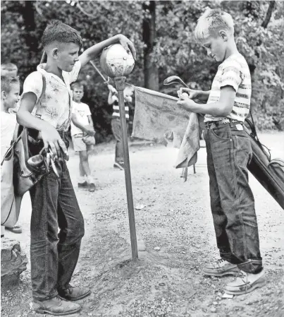  ?? THE COMMERCIAL APPEAL ?? Bobby Jack Mcelya, left, watches as his first-round opponent Dudley Smith washes his ball before teeing off in the Kids' Golf Clinic at Overton Park on Aug. 18, 1953.