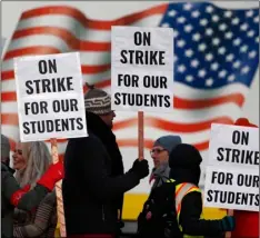  ?? AP Photo/DAVID ZAlubowSkI ?? In this Feb. 11 file photo, teachers carry placards as they walk a picket line outside South High School in Denver.