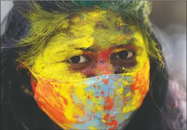  ?? (AP/Rajanish Kakade) ?? An Indian woman smeared in colors looks on during Holi festival in Mumbai. Hindus threw colored powder and sprayed water in massive Holi celebratio­ns Monday despite many Indian states restrictin­g gatherings to try to contain a coronaviru­s resurgence rippling across the country.