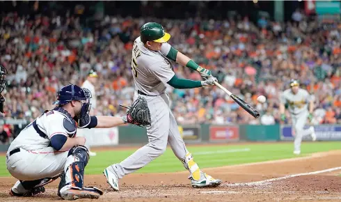  ?? AP Photo/David J. Phillip ?? Oakland Athletics’ Ryon Healy (25) hits a grand slam as Houston Astros catcher Brian McCann reaches for the pitch during the sixth inning of a baseball game Tuesday in Houston.