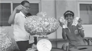  ??  ?? HEAVIEST BUTT – Subic Bay Metropolit­an Authority maintenanc­e worker Mary Ann Dela Cruz gleefully receives cash for the heap of cigarette butts she collected under the SBMA Ecology Center’s Heaviest Butt Campaign, which will pay 1300 for a kilo of the...