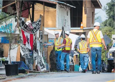  ?? BEN NELMS/THE CANADIAN PRESS ?? Burnaby RCMP and city of Burnaby officials dismantle Camp Cloud near the entrance of the Kinder Morgan Trans Mountain pipeline facility in Burnaby on Thursday.