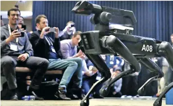  ??  ?? A Boston Dynamics SpotMini robot walks through a conference room during a robotics summit in Boston.