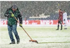  ?? FOTO: DPA ?? Ein Helfer befreit im Spiel Hannover 96 gegen Bayer 04 Leverkusen mit einem Besen die Strafrauml­inie vom Schnee.