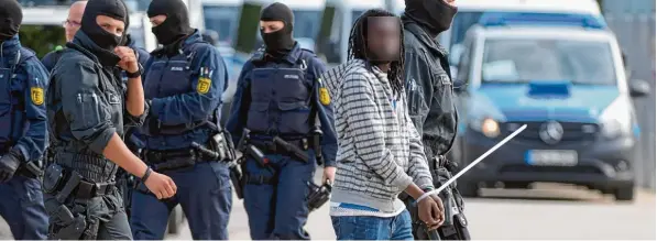  ?? Foto: Stefan Puchner, dpa ?? Maskierte Polizisten führen einen gefesselte­n Flüchtling während der Razzia in der Landeserst­aufnahmeei­nrichtung in Ellwangen ab.