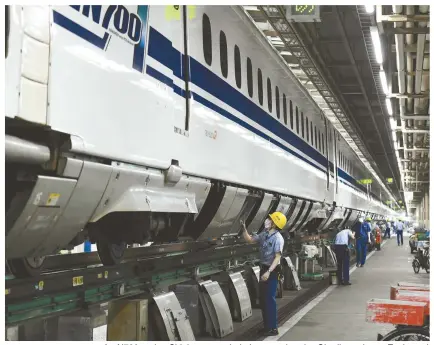  ?? ?? An N700-series Shinkansen train is inspected at the Oi railway depot. Each car is examined by a team of two mechanics, and all of the cars are inspected at the same time.