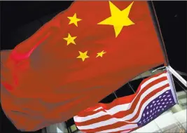  ?? Andy Wong ?? The Associated Press U.S. and Chinese national flags are hung outside a hotel in Beijing. A government report outlines how spy services from China, Russia and Iran are trying to steal proprietar­y informatio­n from U.S. companies, government labs and...