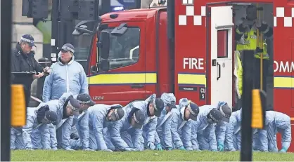  ?? JUSTIN TALLIS, AFP/ GETTY IMAGES ?? Police in forensic suits search the grassed area in Parliament Square outside the Houses of Parliament in central London on Thursday, one day after a terror attack in Westminste­r claimed at least three lives.