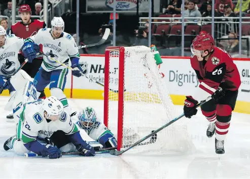  ?? — THE ASSOCIATED PRESS ?? Coyotes centre Nick Cousins shoots on goal as Canucks left winger Antoine Roussel and goaltender Anders Nilsson defend the net on Thursday at Gila River Arena in Glendale, Ariz. The Canucks lost 4-1.