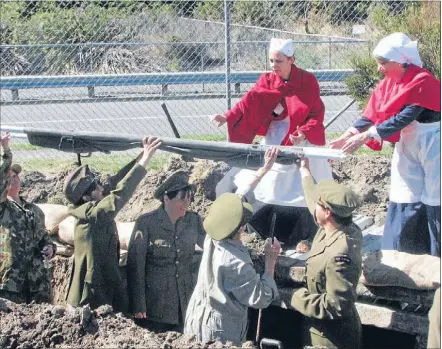  ??  ?? Lest we forget: Pupils and teachers at St Theresa’s marked the battle at Gallipoli by dressing up in uniform. Here nurses help to lower a
stretcher into a trench.