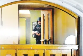 ?? (Nick King/Lansing State Journal via AP) ?? A police officer, with his gun drawn, is seen through the window at an entrance at the Michigan State University Union following shootings on campus on Monday in East Lansing, Mich.