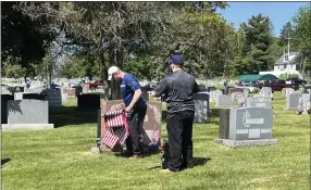  ?? RACHEL RAVINA — MEDIANEWS GROUP ?? George Koder, left, of North Wales, and Patrick Kiely, of Eagleville, prepare to place a flag at a veteran’s gravesite on Saturday at Calvary Cemetery.