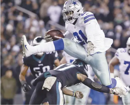  ??  ?? Le demi offensif des Cowboys Ezekiel Elliott saute afin d’éviter un adversaire. - Associated Press: Matt Rourke