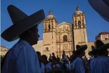  ??  ?? People dressed in traditiona­l attire prepare for a parade in front of the Templo de Santo Domingo de Guzmán.